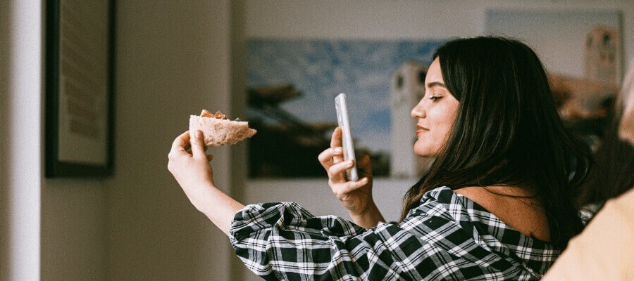 girl taking photo of pizza on smartphone girl taking photo of pizza on smartphone